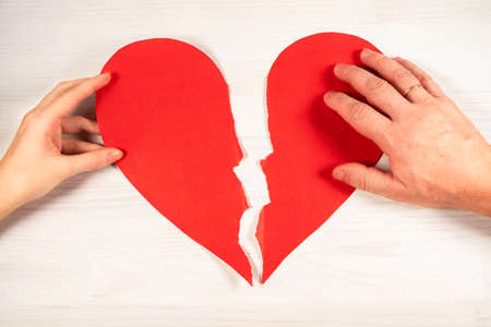 Red paper heart torn by pieces paper. view from above. flat lay. Two torn pieces of one heart. unattractive valentine's day conceptの写真素材