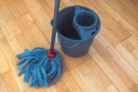 Cleaning parquet floor with rope mop. Mop with tape nozzle and bucket for mopping floor with wring...