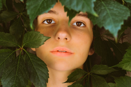 Portrait beautiful young woman with green leaves on faceの写真素材
