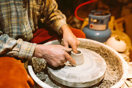 pottery in workshop of ceramist. potter's hands working with clay on potter's wheel, forming bowl. Traditional pottery, craft handicrafts, authentic atmosphereの写真素材