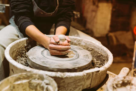 female hands of pottery master close-up work behind potter's wheel. Master class for manufacture of handcrafted ceramic productsの写真素材