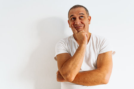 series of emotional portraits of middle-aged man, in white T-shirt, against white wall. Antics, expression of emotions, grimaceの写真素材