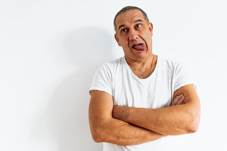 series of emotional portraits of middle-aged man, in white T-shirt, against white wall. Antics,...