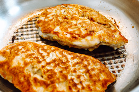 Fried chicken fillet with cheese and crispy crust in frying pan.の写真素材