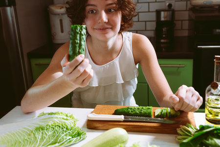 Young woman cutting vegetables in the kitchen. Healthy eating and dieting concept.の写真素材