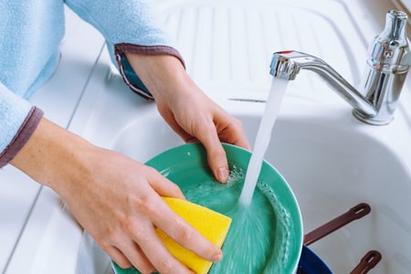 Woman washing dishes in the kitchen sink with sponge and detergent. Concept kitchen morning woman dishwasherの写真素材