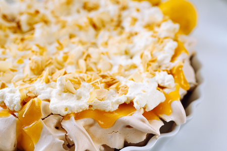 Meringue cake with whipped cream and mango on a white plateの写真素材