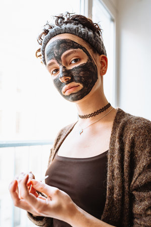 Portrait of a young caucasian woman with clay mask on her face at homeの写真素材