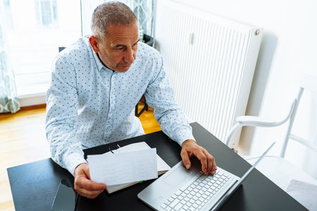 man makes calculations, looks through financial report of home cash registerの写真素材