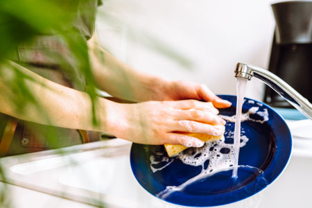 Housework washing dishes after dinner, housewife washes plate under running waterの写真素材