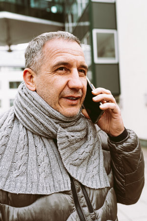 Portrait middle aged person with mobile phone in cityの写真素材