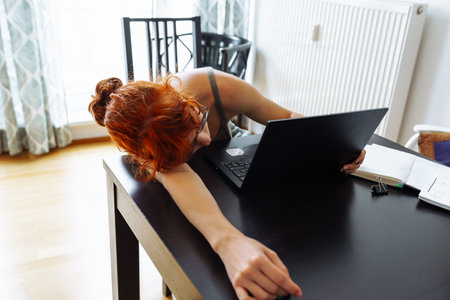 Tired teenager girl studying using computer at homeの写真素材