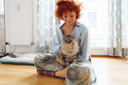 Portrait red-haired curly young woman with beloved fluffy domestic catの写真素材
