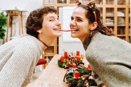 Portrait funny girlfriends eating sausage for advent holidayの写真素材