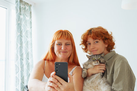 Mom and daughter take selfie with pet cat at homeの写真素材