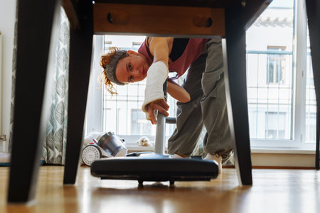 Teen girl helps clean house, vacuums floorの写真素材