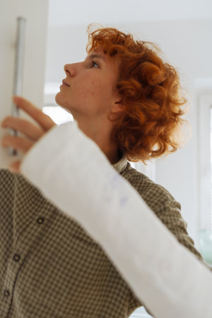teenage girl, with cast on arm, cook lunch at homeの写真素材