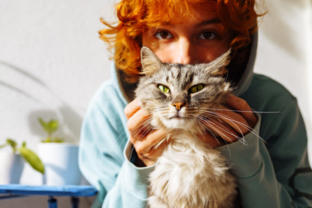 portrait teenage red-haired girl with fluffy green-eyed catの写真素材