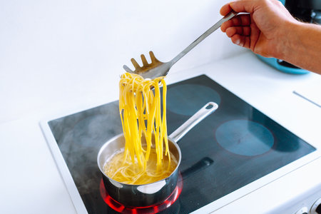 man cooks pasta spaghetti at home in kitchen.の写真素材