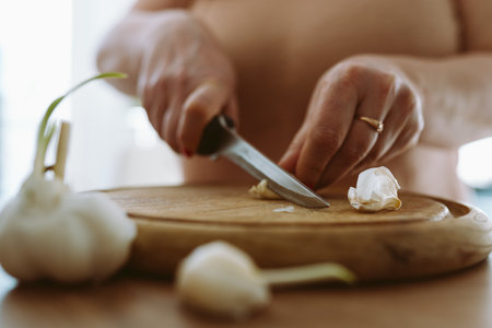 cooking, slicing garlic cloves on wooden cutting boardの写真素材