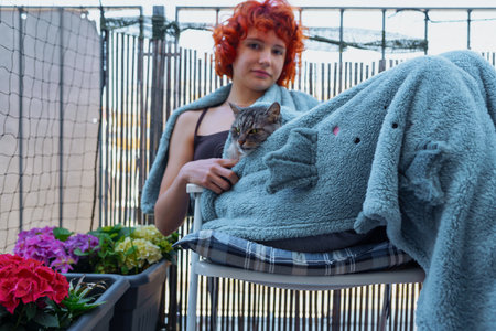 portrait young red-haired woman in plaid with cat, on terraceの写真素材