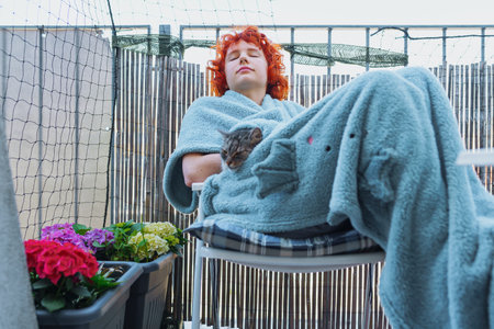 portrait young red-haired woman in plaid with cat, on terraceの写真素材