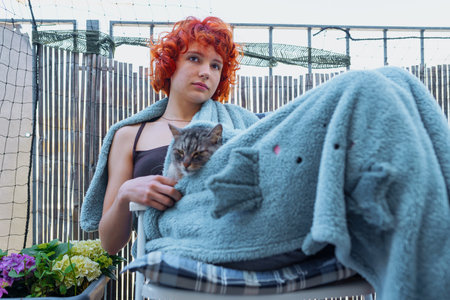 portrait young red-haired woman in plaid with cat, on terraceの写真素材