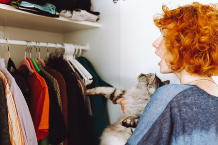 red-haired teenage girl and big cat choose things from closetの写真素材