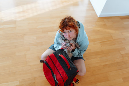 portrait attractive teenage girl with suitcase and pet cat, in an empty apartmentの写真素材