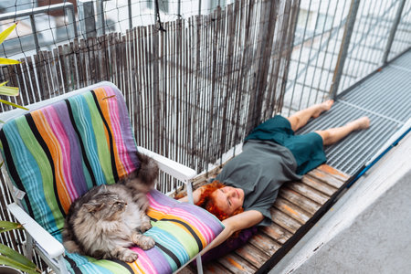 portrait red-haired curly young woman enjoying relaxation on balcony or terraceの写真素材