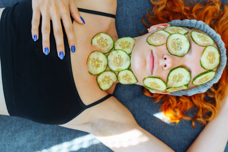 close-up face red-haired young woman with round slices of cucumber, cucumber mask on faceの写真素材