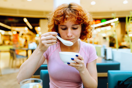 attractive redhead teen girl eating chinese soup in fast food restaurantの写真素材