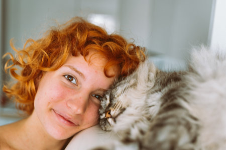 portrait red-haired teenage girl with gray fluffy catの写真素材