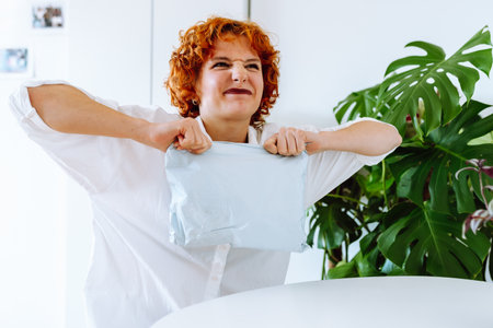 young red-haired attractive woman unpacking parcel at homeの写真素材