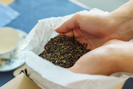 Woman holding paper bag with dry green tea leaves, close upの写真素材