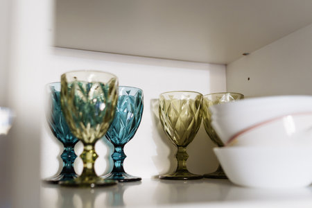 Clean dishes and tableware on white shelf