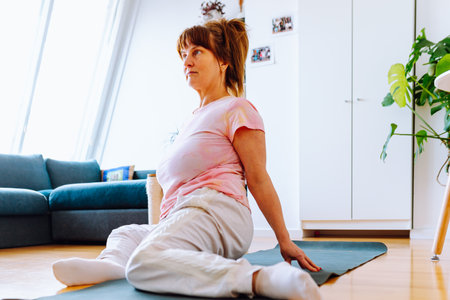 middle aged woman doing yoga at homeの写真素材