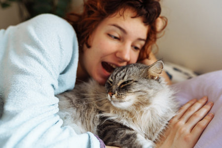 sleeping young woman on bed with pet catの写真素材