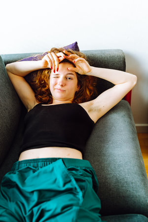 young red-haired woman tired lies on sofaの写真素材