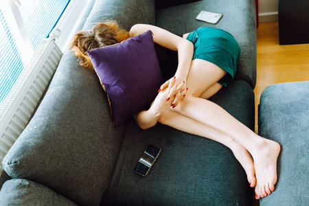 young red-haired woman tired lies on sofaの写真素材