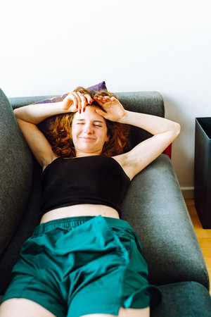 young red-haired woman tired lies on sofaの写真素材