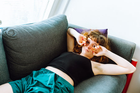 young red-haired woman tired lies on sofaの写真素材