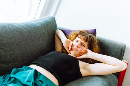 young red-haired woman tired lies on sofaの写真素材