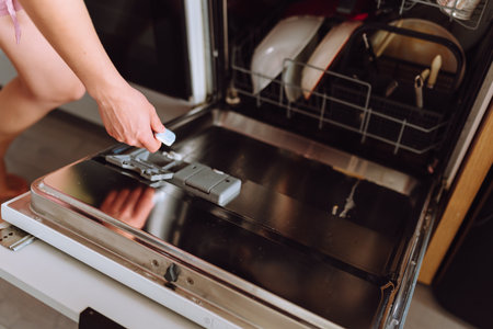 young woman using dishwasher in home kitchenの写真素材