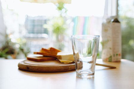 An empty glass stands on table, in background there is bread, butter, milk. Breakfastの写真素材