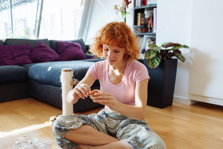 teenage girl assembles construction set according to instructions sitting on floor in roomの写真素材