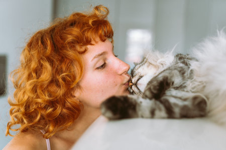portrait red-haired teenage girl with gray fluffy catの写真素材