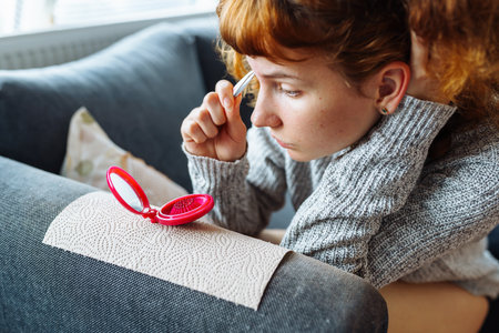 young woman looks at facial skin in mirrorの写真素材