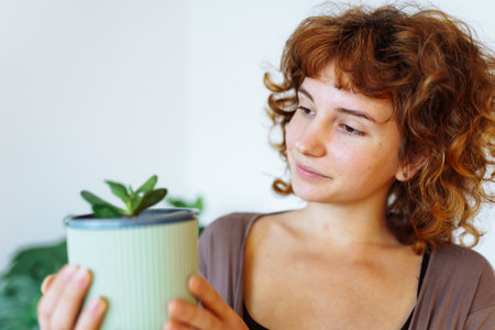 young girl holds flowerpot with plant in hands