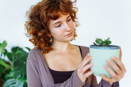 young girl holds flowerpot with plant in handsの写真素材
